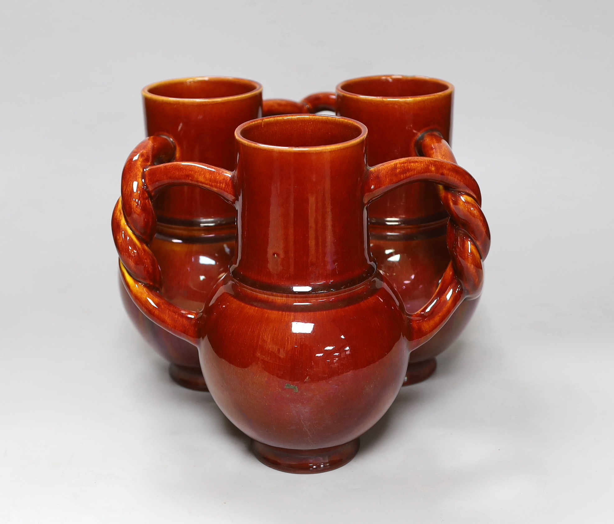A Burmantofts Pottery three section fuddling cup with interwoven handles in dark burnt orange, stamped with marks to base, height 21cm